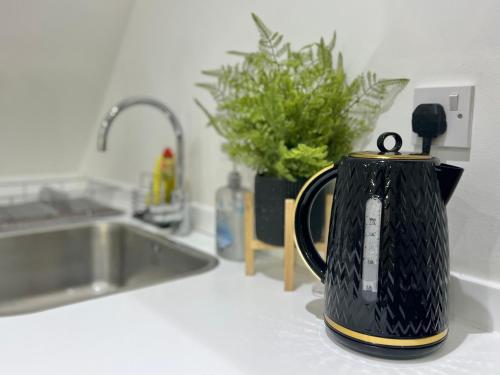 a black tea kettle sitting on a counter next to a sink at 2-bed flat in central Borehamwood location in Borehamwood