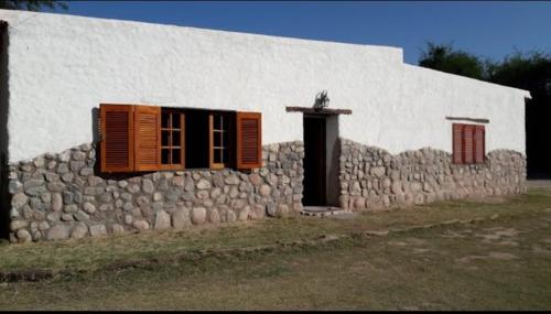 un edificio con ventanas y pared de piedra en Hotel de campo luna en Tinogasta