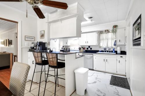 una cocina blanca con armarios blancos y taburetes de bar en North Park - A Birdy Vacation Rental en San Antonio