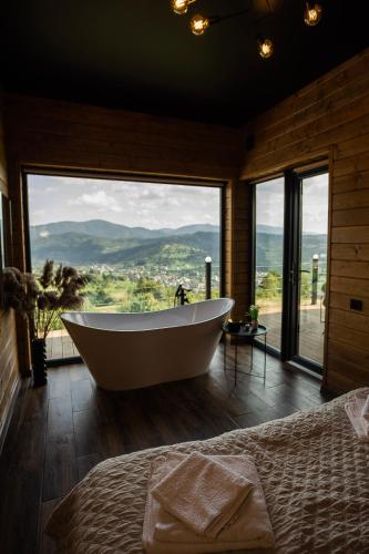 a bath tub in a room with a large window at Under Sky Slavske - Котеджі з Теплим басейном ,чаном-джакузі, панорамною ванною та PlayStation 5 in Slavske