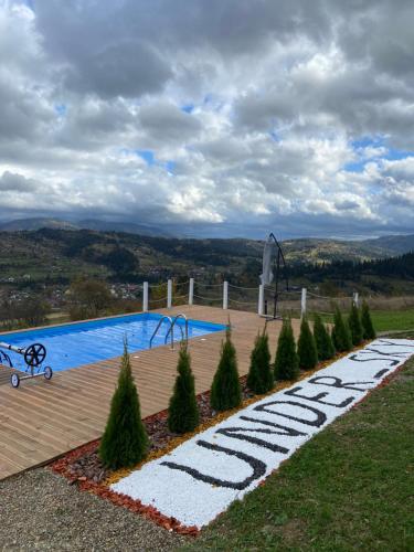 a swimming pool with trees in front of it at Under Sky Slavske - Котеджі з Теплим басейном ,чаном-джакузі, панорамною ванною та PlayStation 5 in Slavske