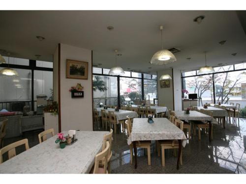 a restaurant with tables and chairs and windows at Hotel New Yutaka - Vacation STAY 35266v in Izumi-Sano