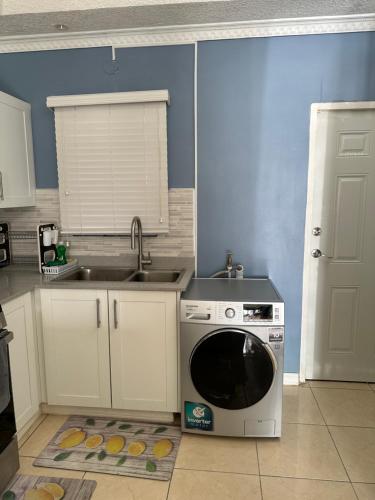 a kitchen with a washing machine and a sink at The Cameron @ Phoenix Park in Portmore
