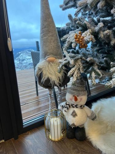 a snowman and a christmas tree in front of a window at Under Sky Slavske - Котеджі з Теплим басейном ,чаном-джакузі, панорамною ванною та PlayStation 5 in Slavske