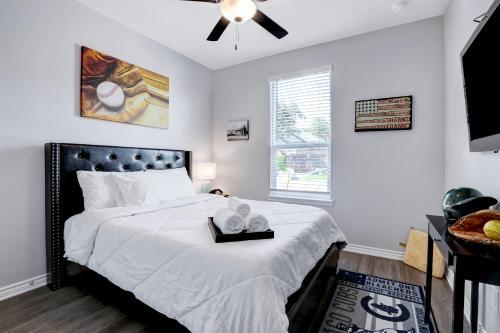a bedroom with a bed with white sheets and a ceiling fan at Overtime - A Birdy Vacation Rental in Boerne