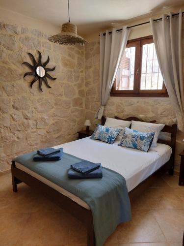 a bedroom with a bed and a stone wall at cottage du soleil in Makry Gialos