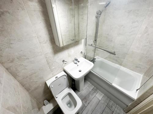 La salle de bains est pourvue de toilettes, d'un lavabo et d'une baignoire. dans l'établissement Camden Apartment, à Londres