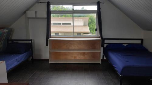a attic room with two beds and a window at Maison Moehau Iti in Moorea