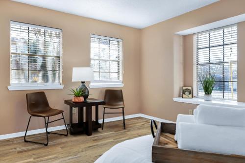 a bedroom with a white bed and two chairs and windows at Pong - A Birdy Vacation Rental in San Antonio