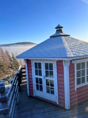 a small red house with a roof on a deck at Daviot Luxury Pods in Inverness