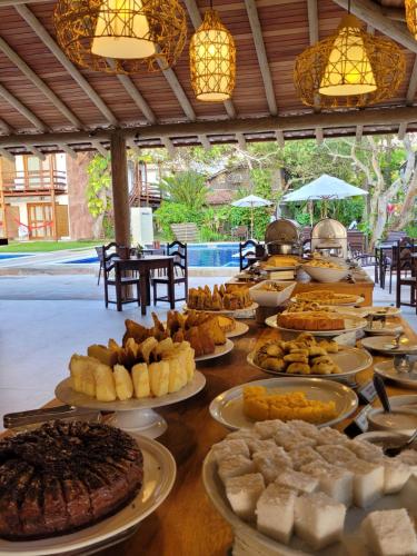 a table with many different types of food on plates at Aquarela Praia Hotel in Arraial d'Ajuda