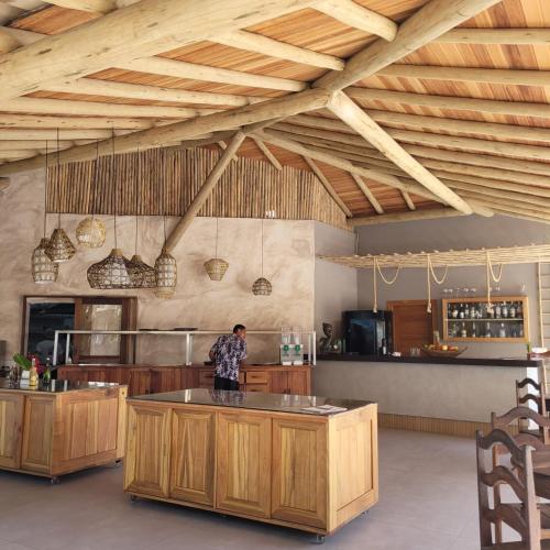 a man standing in a large kitchen with wooden cabinets at Aquarela Praia Hotel in Arraial d'Ajuda