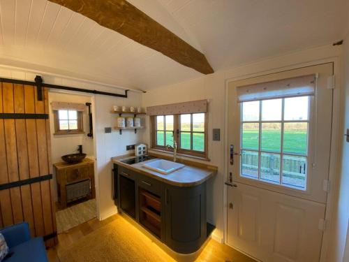 una pequeña cocina con fregadero y ventana en Luxury Shepherd Hut en Kelham