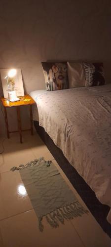 a bedroom with a bed and a table with a lamp at Mimi House in Rio de Janeiro