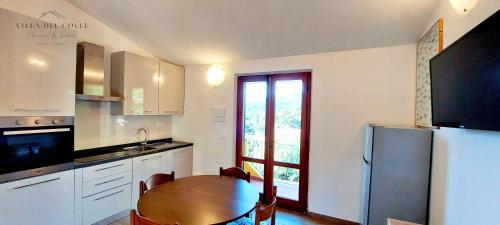 a kitchen with a wooden table and a refrigerator at Villa del Colle Charme e Relax in Procchio