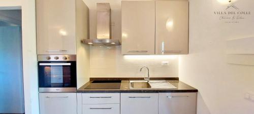 a kitchen with white cabinets and a sink at Villa del Colle Charme e Relax in Procchio