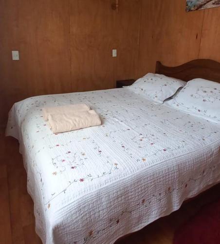 a bed with a white comforter with a towel on it at cabañas Cadiz in Valdivia