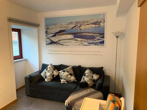 a living room with a black couch and a painting at Casa da Carvalha - Loriga in Loriga