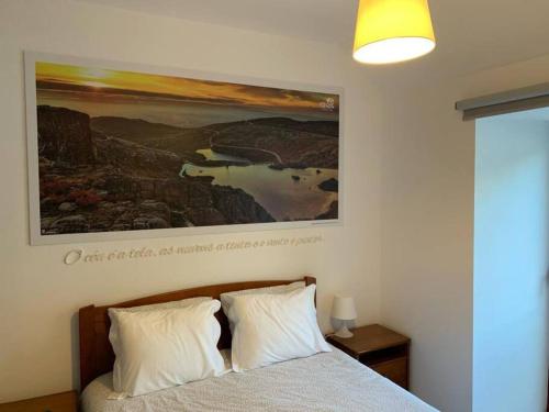 a bedroom with a bed with a painting on the wall at Casa da Carvalha - Loriga in Loriga
