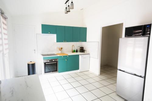Il comprend une cuisine avec des placards verts et du carrelage blanc. dans l'établissement Charmant appartement au cœur de Saint-peray, à Saint-Péray
