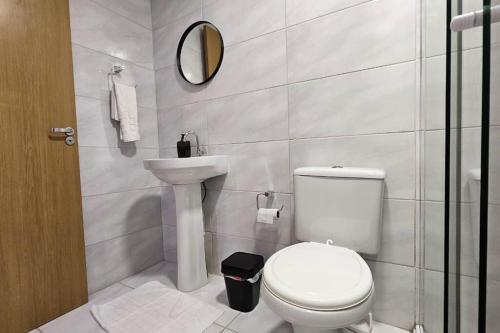 uma casa de banho com um WC, um lavatório e um espelho. em Apartamento moderno em excelente localização em Bento Gonçalves