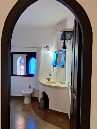 un arco che conduce a un bagno con lavandino e servizi igienici di Dar Gabriel a Chefchaouen