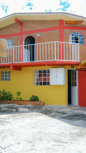 a yellow and red house with a balcony at Hotel Real de San Antonio in Estanzuela