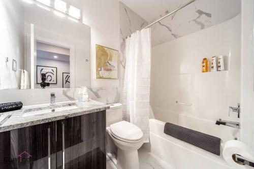 a white bathroom with a toilet and a sink at La Maison, Near University & DT, 2BR Bsmt Suite, King Bed! in Edmonton