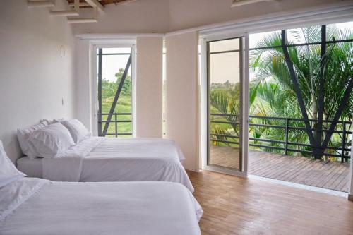 two beds in a white room with a balcony at Hotel Casa Natura in Pereira
