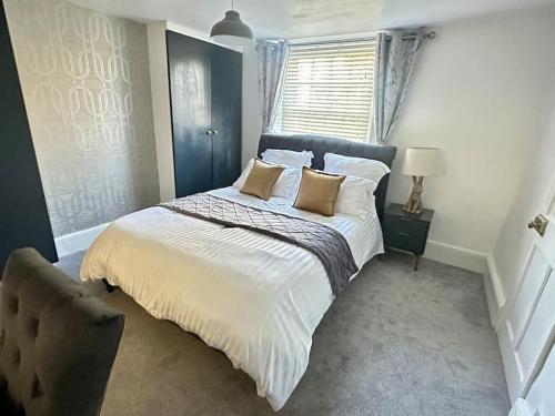 a bedroom with a bed with pillows and a window at Historic Charm: *Perfect For Group Getaways* in Trowbridge