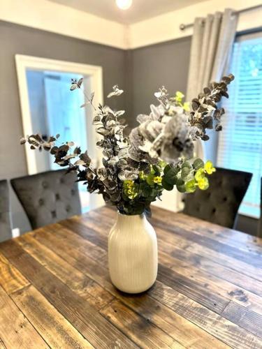 a white vase with flowers on a wooden table at Historic Charm: *Perfect For Group Getaways* in Trowbridge