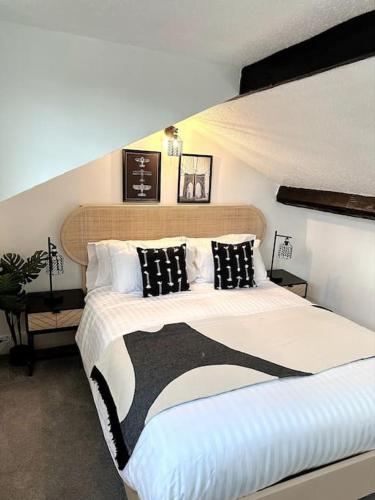 a bedroom with a large bed with black and white pillows at Historic Charm: *Perfect For Group Getaways* in Trowbridge