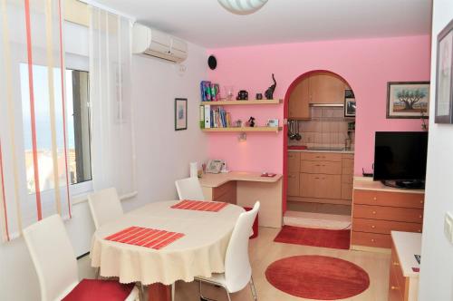 a room with a table and a kitchen with pink walls at Apartment BM ST2 in Split