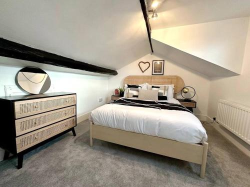 a bedroom with a bed and a dresser with a mirror at Historic Charm: *Perfect For Group Getaways* in Trowbridge