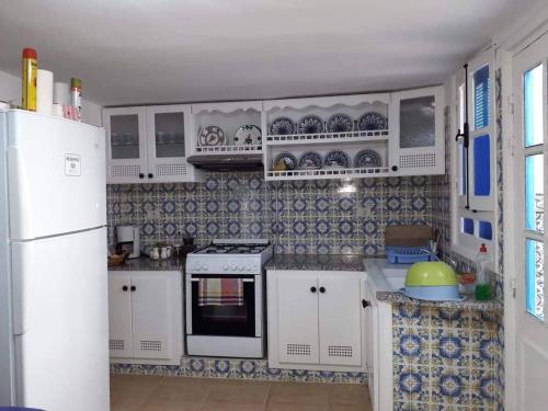 cocina con armarios blancos y nevera blanca en Dar El Goulli, en Hammam Sousse