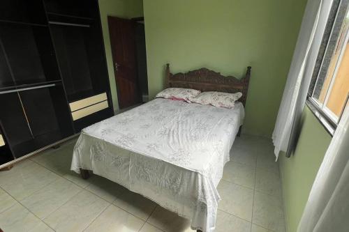 um quarto com uma cama com lençóis brancos e uma janela em Apartamento em Setiba em Guarapari