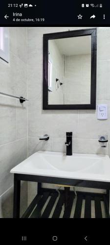 ein Badezimmer mit einem weißen Waschbecken und einem Spiegel in der Unterkunft Apart Mi Kaú in Catriel