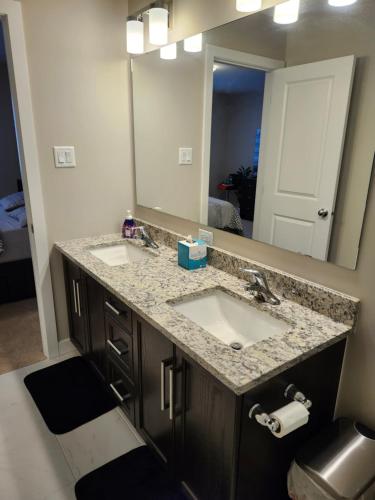 un bagno con due lavandini e un grande specchio di Brand New-Budget friendly master bedroom-House a Carleton Place