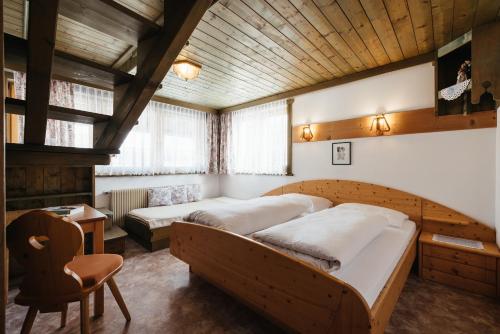 a bedroom with two beds and a chair at Apartments Roda de Ciar in Badia