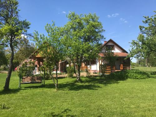 ein Haus inmitten eines Feldes mit Bäumen in der Unterkunft Csörgő Vendégházak in Szalafő
