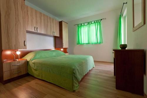 1 dormitorio con 1 cama con edredón verde en Apartments Branka, en Podgora