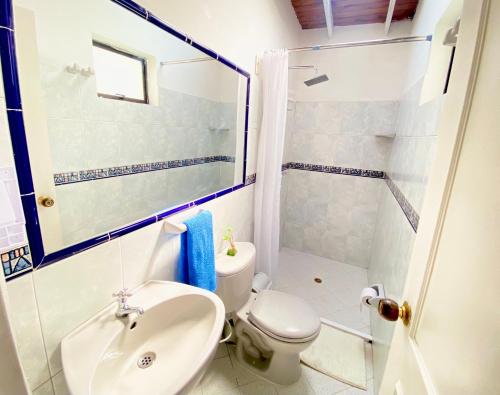 ein Bad mit einem WC, einem Waschbecken und einer Dusche in der Unterkunft Acogedoras habitaciones en casa compartida in Medellín
