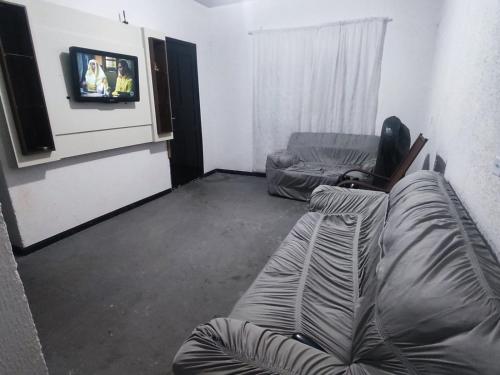 a living room with a couch and a tv at Casa aconchego com piscina in Guaratuba
