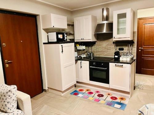 a kitchen with white cabinets and a kitchen rug on the floor at Incantevole Appartamento con Giardino - Free WiFi e Private Garage in Oulx