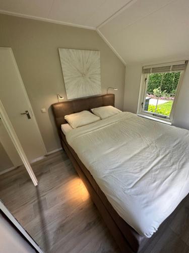 1 dormitorio con 1 cama grande y ventana en Bungalow Veluws Vertoeven en Putten