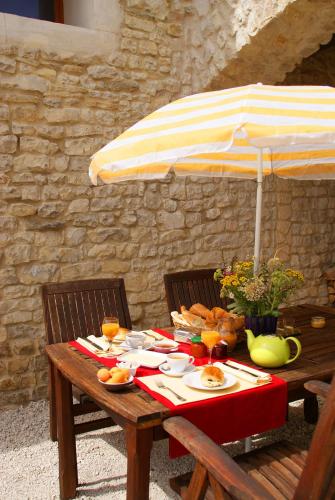 een houten tafel met een parasol en eten erop bij Chez Catharina Oldtimer B&B in Levoncourt
