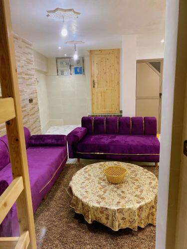 a living room with a purple couch and a table at Apartement au Bord de la Mer TOURMA in Taghazout