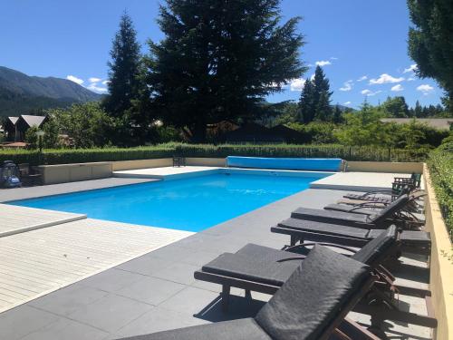 a swimming pool with chaise lounge chairs next to it at Hanmer Garden Suites in Hanmer Springs