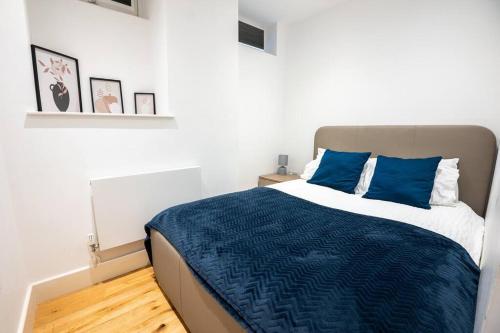 a bedroom with a large bed with blue pillows at Cosy 2 Bed Apartment, East Croydon in Croydon