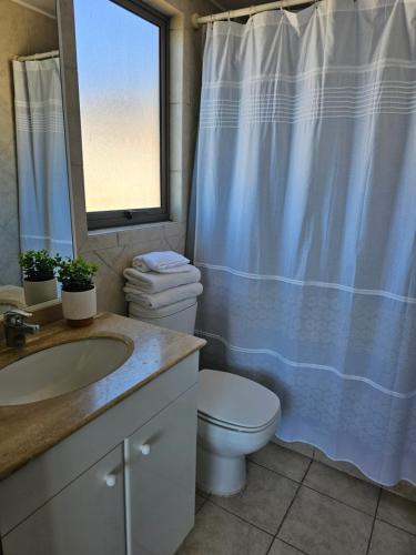 a bathroom with a toilet and a sink and a window at Espectacular Bahía Bonita depto 41 in Concón